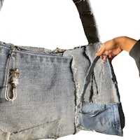 a person holding a denim purse with a zipper